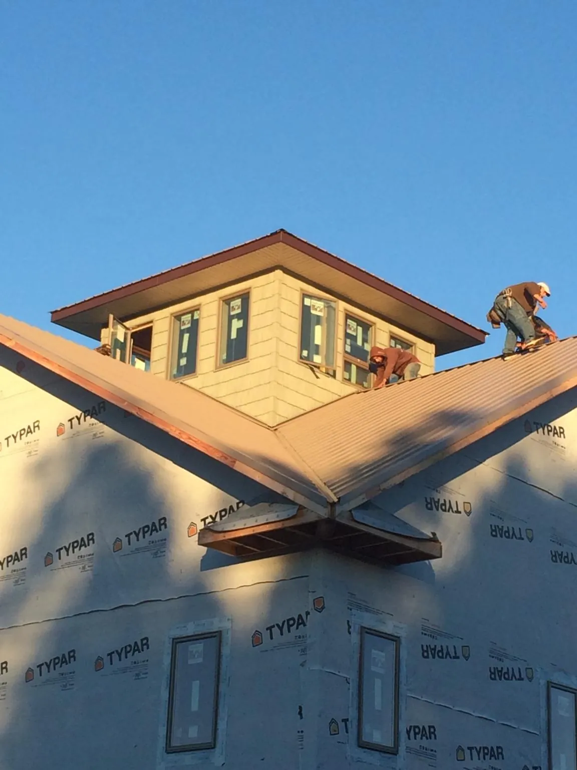 Roofers working around a rooftop cupola on a new metal roof at sunset — Roof Waterproofing in Pembroke by Roofing Brothers
